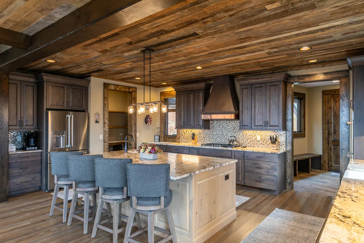 A beautifully designed kitchen shines with a massive granite island, warm wooden cabinetry, double ovens, and modern pendant lighting. Bar stools at the island hint at a space perfect for both cooking and casual socializing.