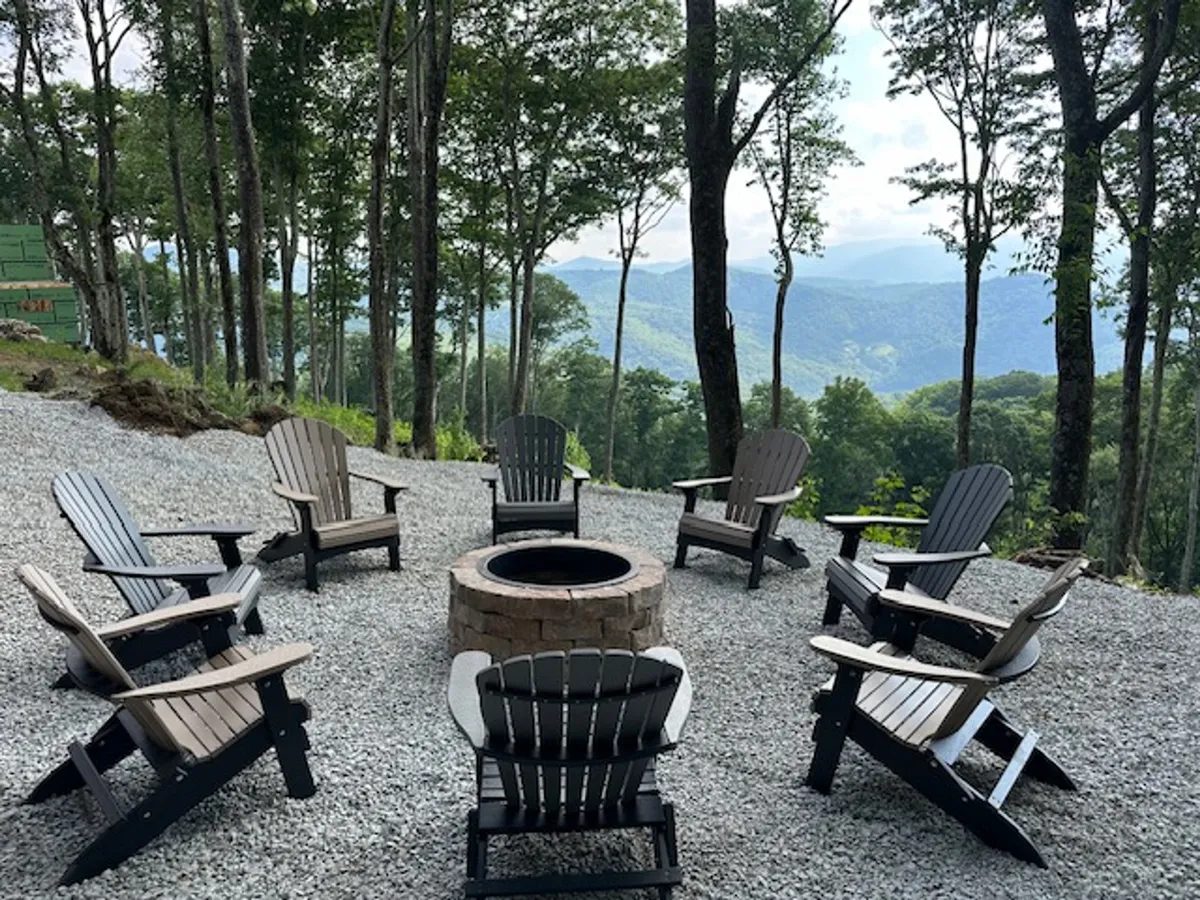 An inviting fire pit area surrounded by Adirondack chairs overlooks expansive mountain vistas. The setting is perfect for campfire gatherings, storytelling, stargazing, and unwinding after a day of activity.